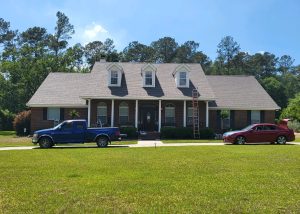 Roofers inspecting and working on a two-story house with a steep roof pitch.