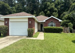 Residential brick house with new roof installation and well-maintained lawn.