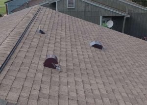 Roofers installing a new asphalt shingle roof on a residential home in Tallahassee, Florida.